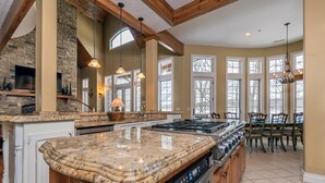 A spacious kitchen with granite countertops, a large island, and a dining area with wooden chairs.
