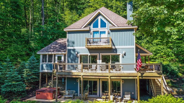 A two-story house with a balcony, a hot tub, and a deck with outdoor furniture. - Canadian Day 4 Bedroom House (McHenry)