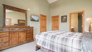 Une chambre à coucher avec un grand lit, une commode en bois et un ventilateur de plafond.