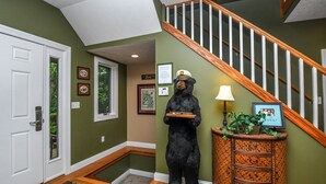 Eine Bärenstatue in einer Diele mit einer Holztreppe und einer Lampe.