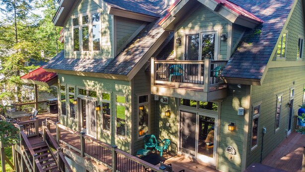 A two-story house with a balcony, large windows, and a deck area.