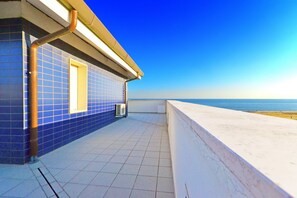 A tiled balcony with a view of the sea, a tiled wall, and a window. - Residence Blu (Lignano Sabbiadoro)