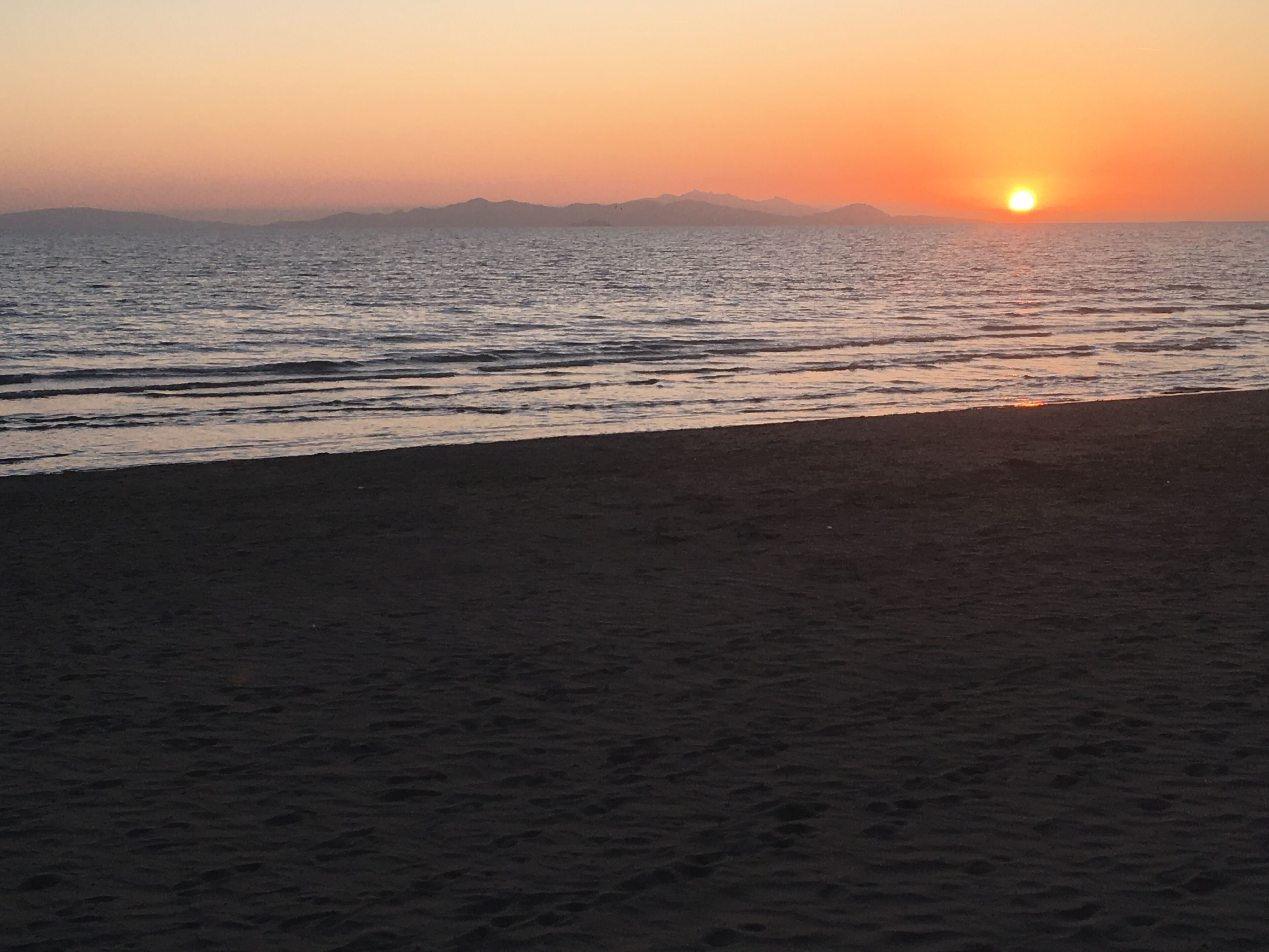 A beach with a sunset over the water.
