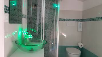 A bathroom with a glass bowl sink, a toilet, and a shower enclosure.