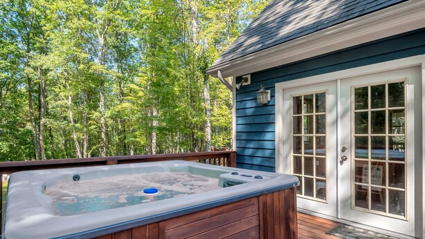 A hot tub on a wooden deck with a view of a forest.