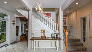 A staircase with a wooden handrail and beige carpeted steps leading to a door.