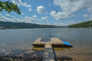 A wooden dock extending into a lake with a boat tied to it.