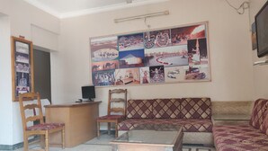 A living room with a sofa, chairs, a coffee table, and a wall collage. - Hotel Leela Nikunj (Jaisalmer)
