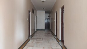 A long, narrow hallway with a marble floor and doors on both sides. - Hotel Leela Nikunj (Jaisalmer)