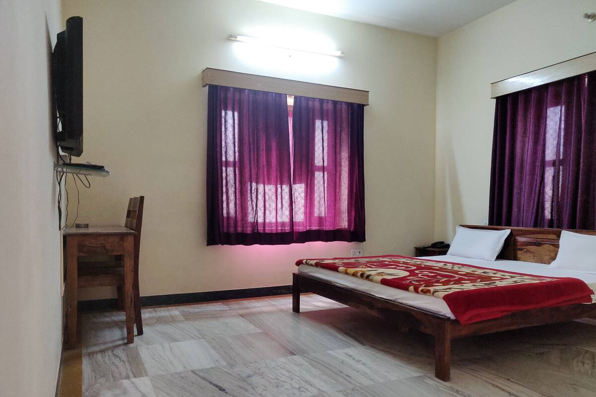 Un dormitorio con cama, escritorio y televisor en la pared.
