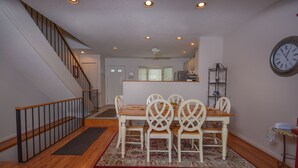 A dining area with a wooden table and chairs, a staircase, and a clock on the wall. - Deep Creek Village 3 Bedroom Townhome #20 (McHenry)