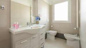 A modern bathroom with a large sink, a toilet, and a bidet.