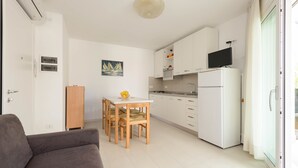 A compact living space with a kitchenette, a dining table with chairs, a sofa, and a television.