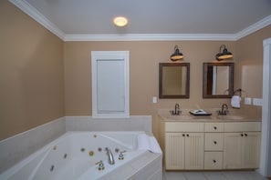 A bathroom with a large bathtub, two sinks, and a mirror. - Lakeside Story 6 Bedroom House (Swanton)