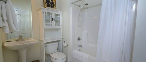 A bathroom with a sink, toilet, bathtub, and shower curtain.