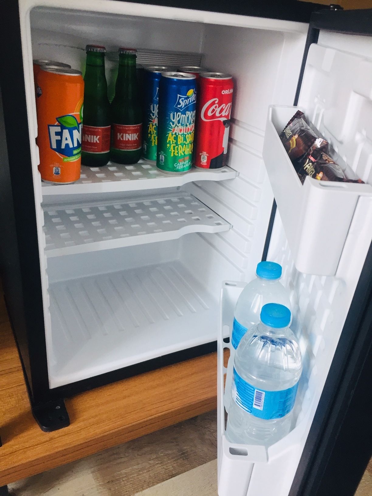 A refrigerator with various beverages including Fanta, Sprite, and Coca-Cola.