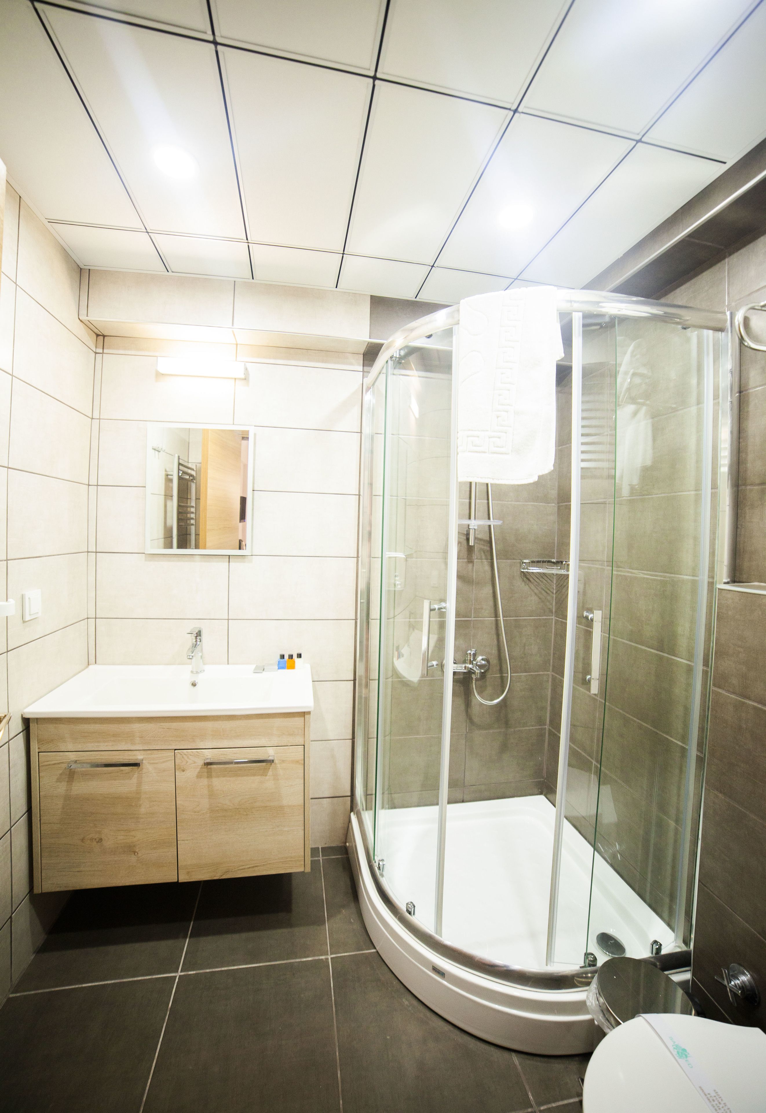 A modern bathroom with a glass-enclosed shower, a wooden vanity, and a white sink.