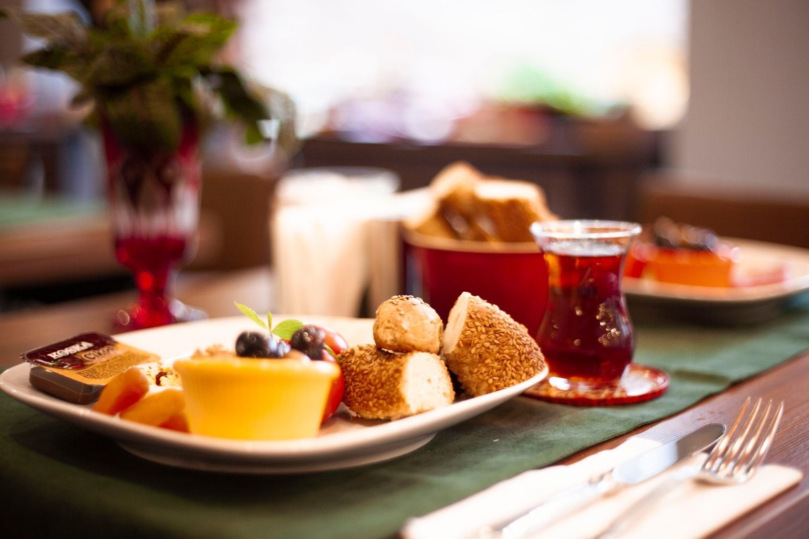 A dining table with a plate of food, a glass of red drink, and a candle.