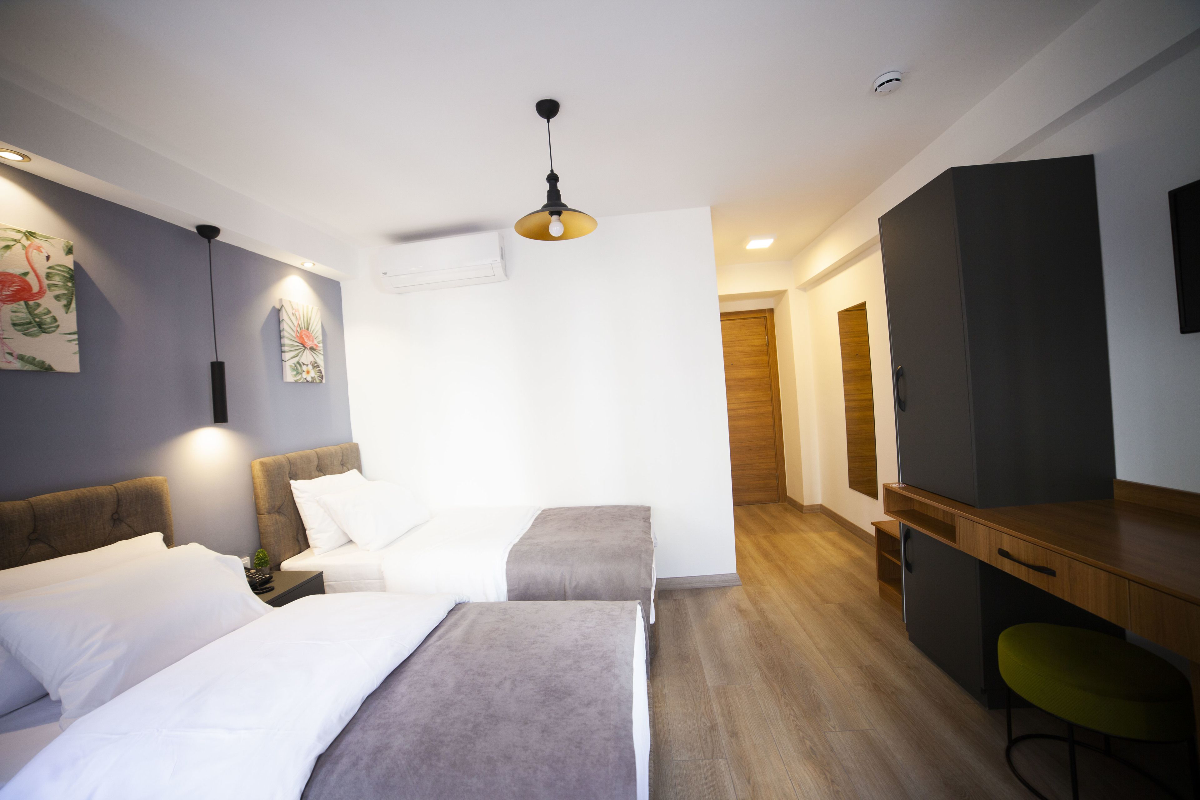 Ett modernt hotellrum med två sängar, ett skrivbord, en stol och en tv.