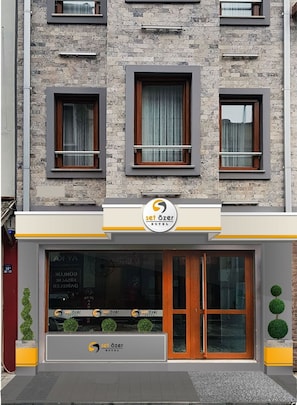 Entrada de un hotel con fachada moderna, un logotipo y un cartel que indica que es un Set Özer Hotel.