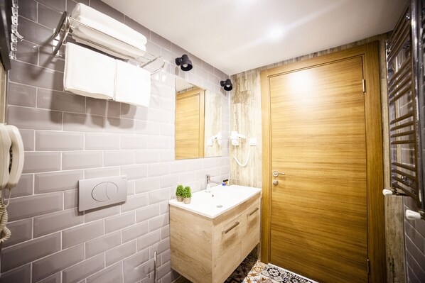A bathroom with a wooden vanity, a white sink, a mirror, and a towel rack.