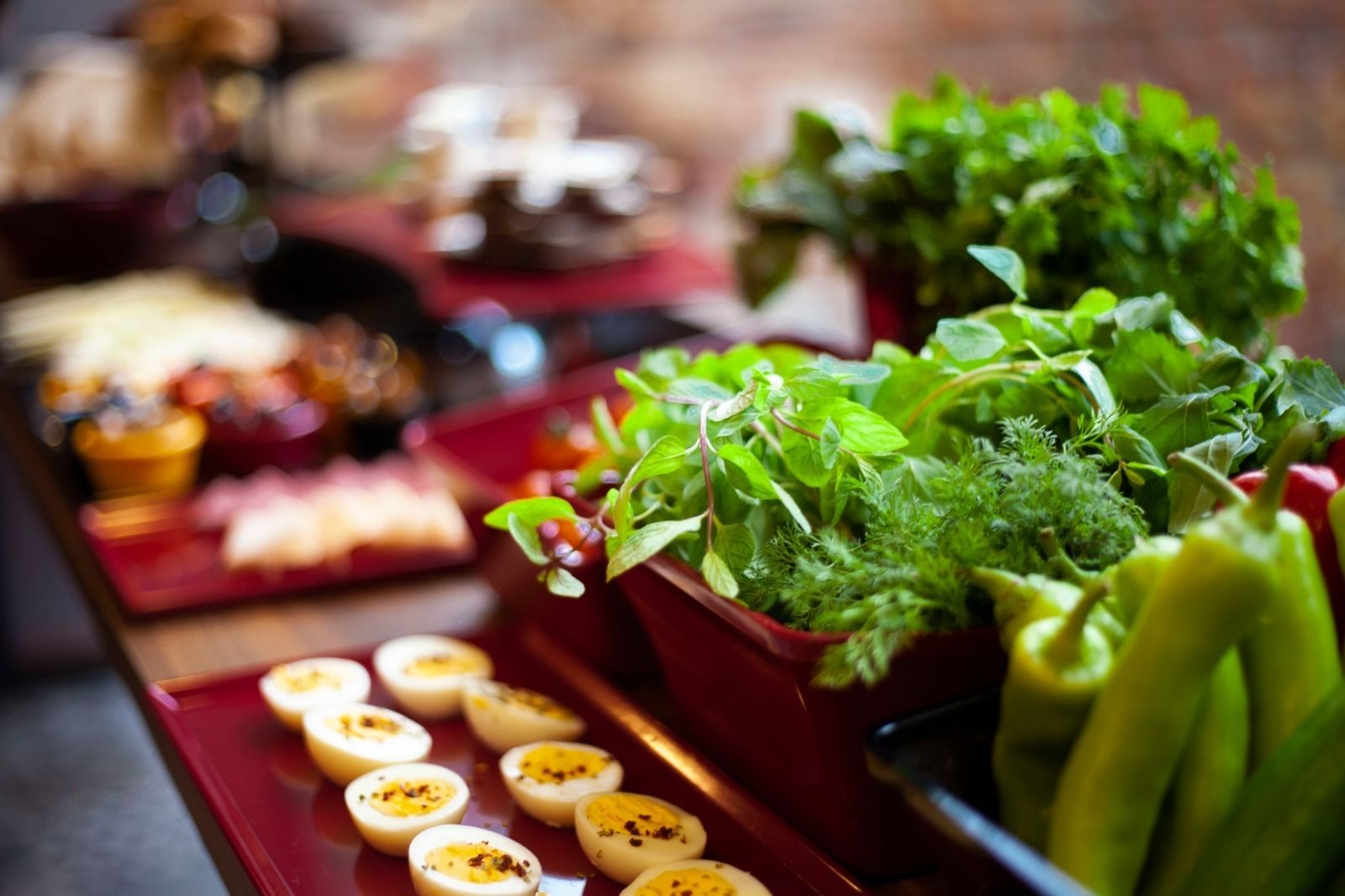 A buffet table with various food items including sliced vegetables, eggs, and green peppers.