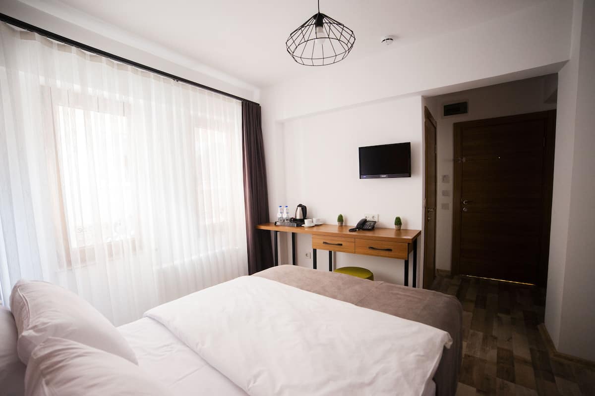 Habitación de hotel con una cama, un escritorio con computadora, televisión y una puerta.