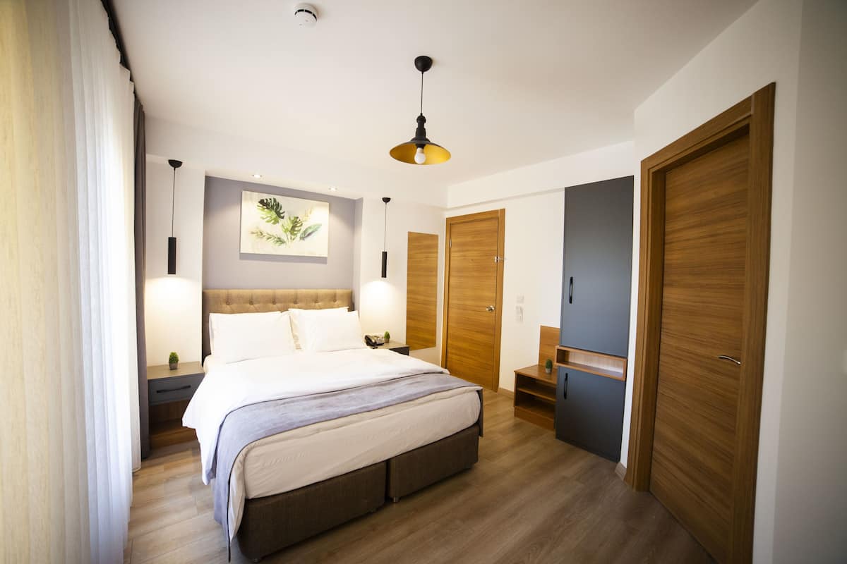 Un dormitorio con una cama grande, armario de madera, mesitas de noche y una lámpara en el techo.
