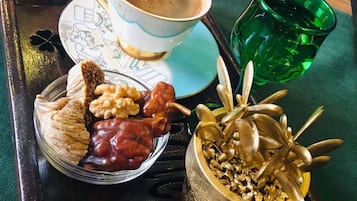 Una bandeja con una taza de café, un vaso verde, un plato de pasteles y un cuenco decorativo.