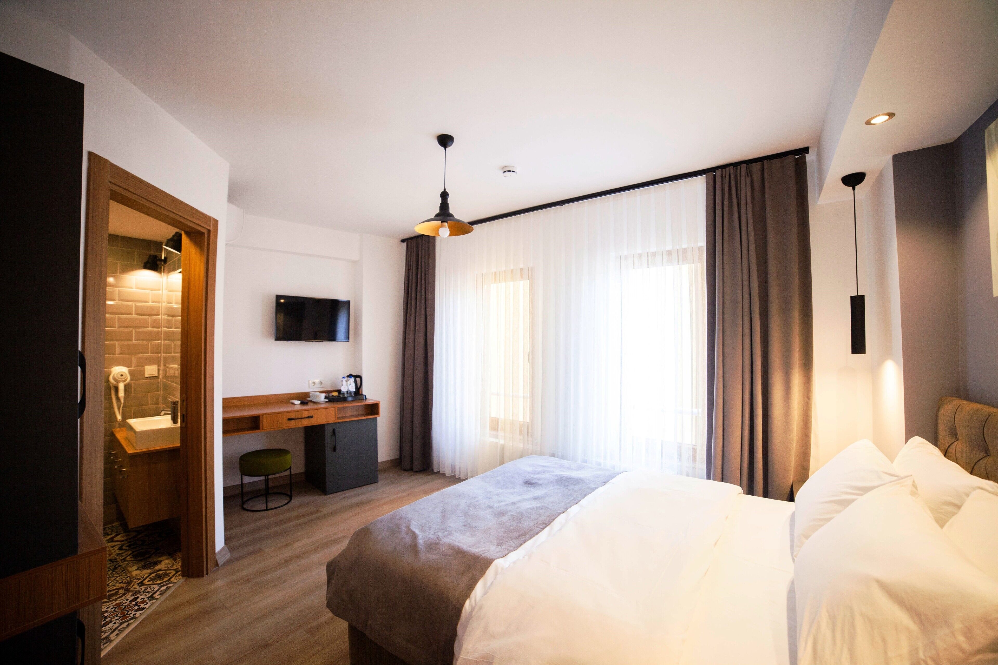 Una habitación de hotel moderna con una cama grande, un escritorio y un televisor.