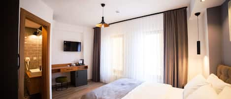 Une chambre d’hôtel moderne équipée d’un grand lit, d’un bureau et d’une télévision.