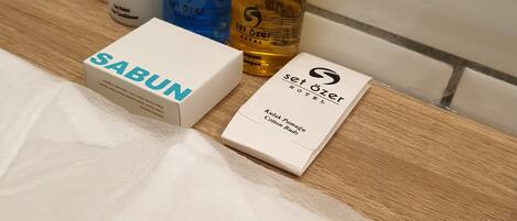 A hotel towel with the hotel logo, a Sabun shampoo box, and two bottles of Set Ozer hotel products.
