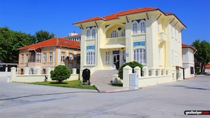 A large, multi-story building with a red-tiled roof and a central entrance with steps. - Set Ozer Hotel (Çanakkale)