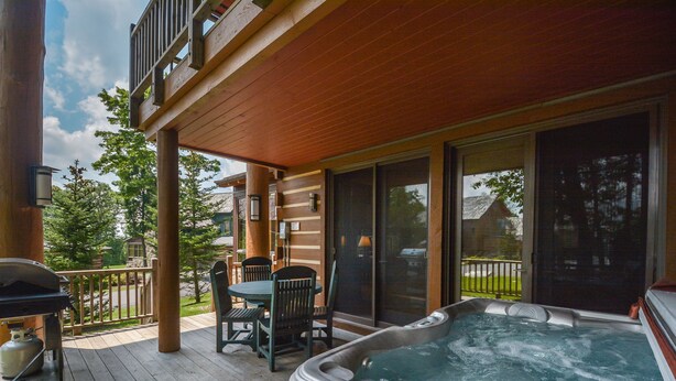 A wooden deck with a hot tub, outdoor furniture, and a grill. - Retreat on Main Street 4 Bedroom Townhome (McHenry)