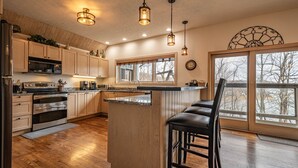 Una cucina moderna con mobili in legno, elettrodomestici in acciaio inossidabile e una grande isola con sgabelli da bar.