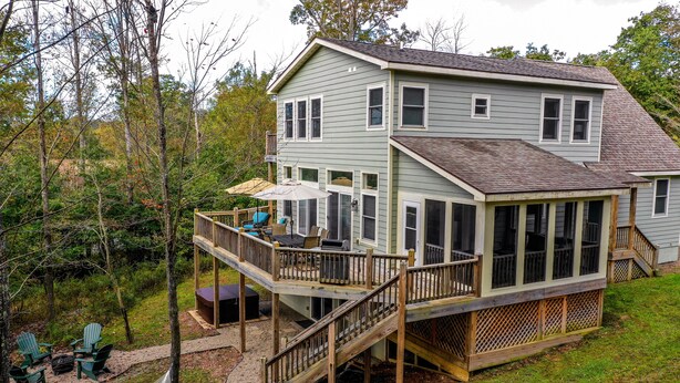 A two-story house with a deck, outdoor seating, and a staircase.