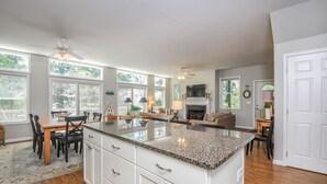 A spacious kitchen with a large island, white cabinetry, and a dining area with a table and chairs.