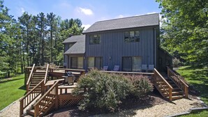 A two-story building with a deck and outdoor seating area. - Sunrise 4 Bedroom House (Oakland)