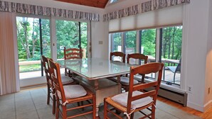 A dining area with a glass-top table surrounded by wooden chairs with cushioned seats. - Sunrise 4 Bedroom House (Oakland)