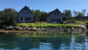 To huse ved en rolig sø med en stenet bred.