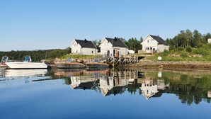 En ejendom ved vandet med flere huse, en anløbsbro og både.