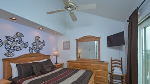 A bedroom with a bed, a dresser, a mirror, a television, and a ceiling fan.
