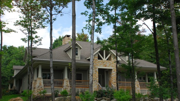A two-story house with a stone facade, a wrap-around porch, and a stone chimney. - Stone Mountain Vista 5 Bedroom House (McHenry)