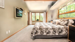 A bedroom with a large bed, a television, and a window with curtains. - Brief Respite 5 Bedroom House (Swanton)