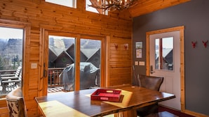 A wooden interior with a dining table, chairs, and a chandelier.