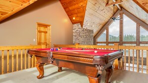 A pool table in a room with wooden beams and a stone wall. - Celebration at Deep Creek 8 Bedroom House (Oakland)