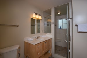 A bathroom with a double sink vanity, a glass shower enclosure, and a towel rack. - All About the View 4 Bedroom House (Oakland)