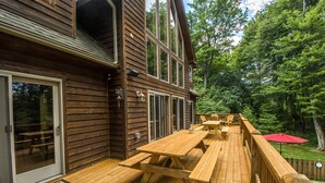 A wooden deck with picnic tables and a red umbrella. - Midnight Dip 6 Bedroom House (Swanton)