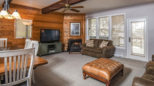 A cozy living room with a fireplace, wooden walls, a television, and a comfortable seating area.