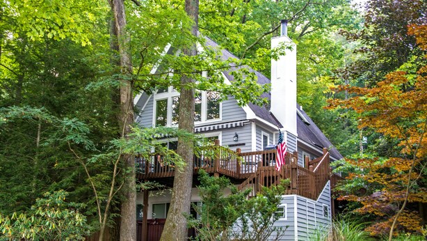 A two-story house with a wooden deck and a flag. - Summer Haven 4 Bedroom House (Oakland)